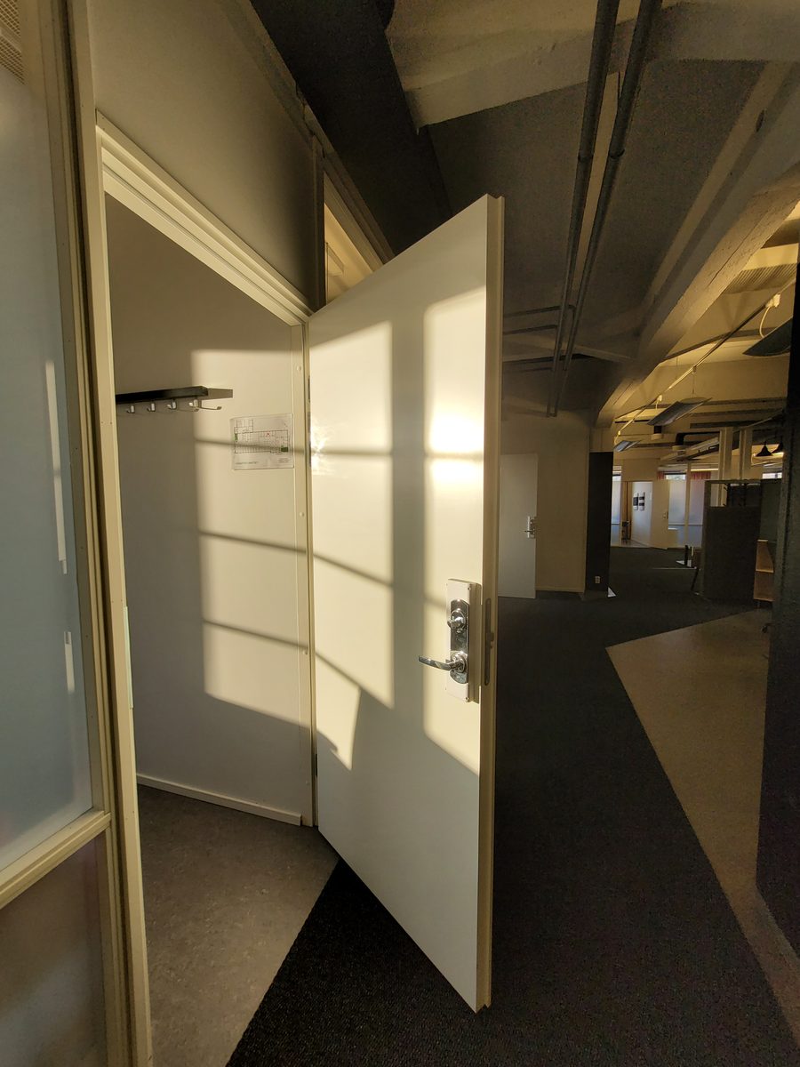 An ordinary-looking white office door standing open, with a plain lever handle