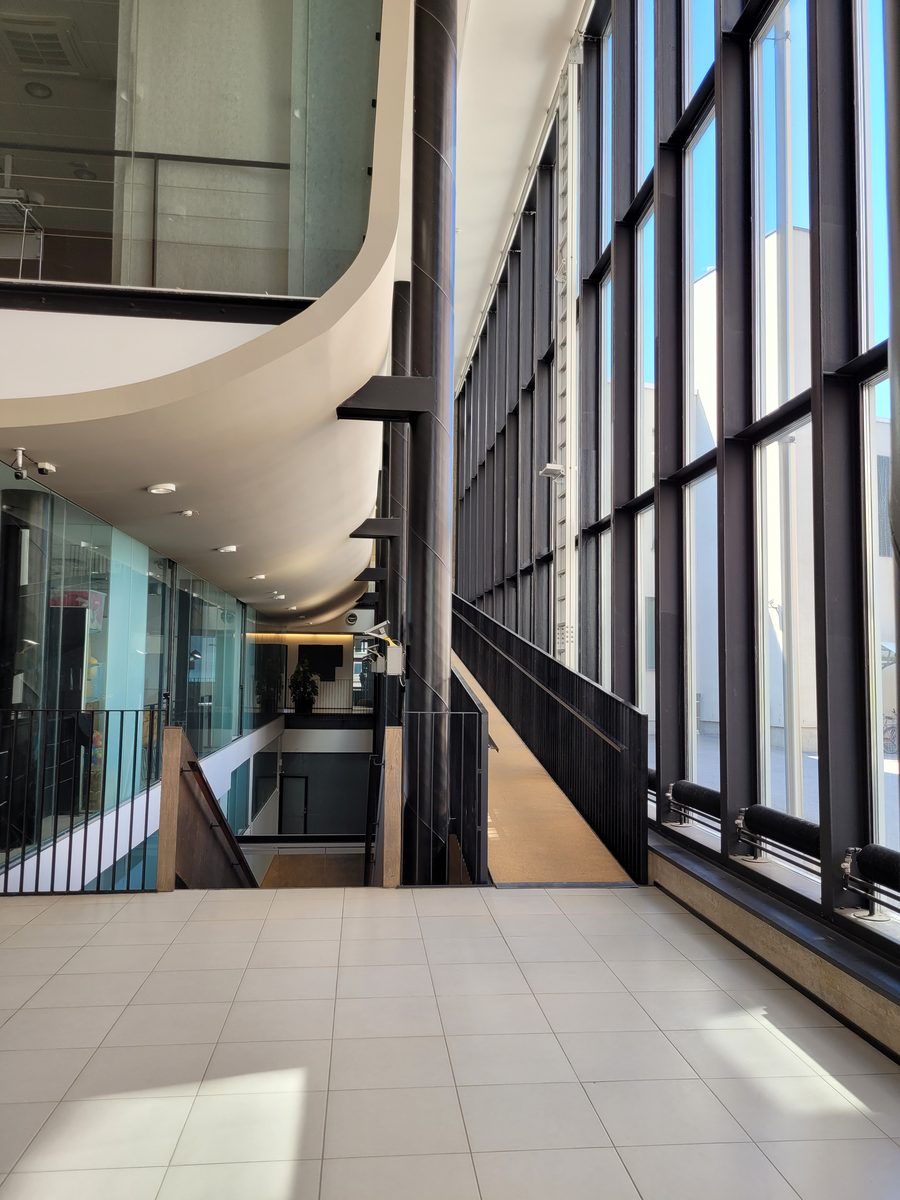 The atrium of a Ylva property, a curved balcony above a stairwell and a wall of tall windows